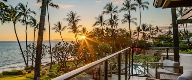 Oceanfront Maui vacation rental with sunset views, palm trees, and beachfront deck overlooking Ulua Beach